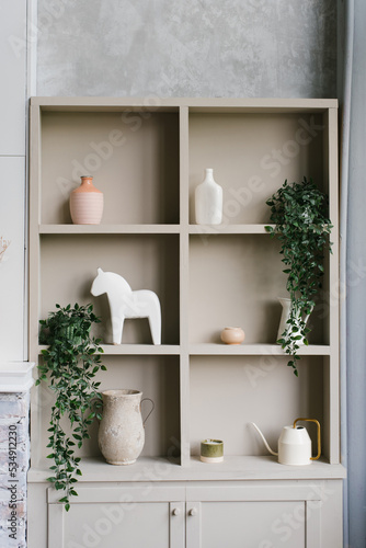 Open cabinet with shelves decorated with vases and indoor plants in Scandinavian style © Sunshine