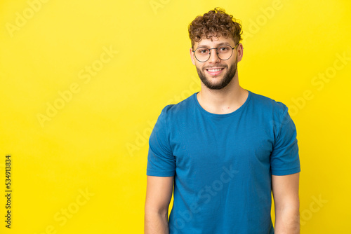 Young handsome caucasian man isolated on yellow background laughing