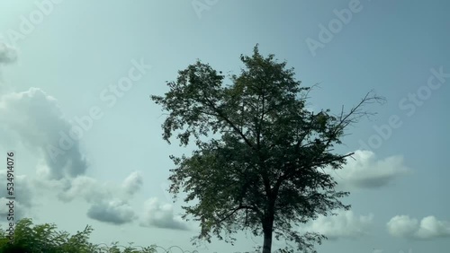 blue sky with clouds, view through the window of moving car on the road