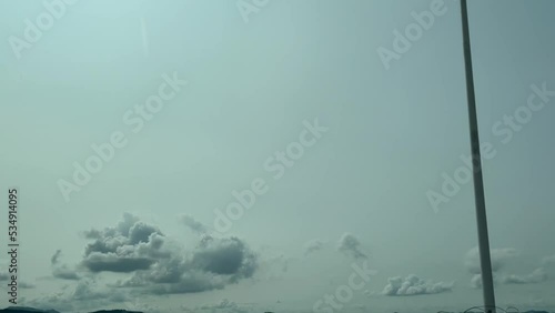 blue sky with clouds, view through the window of moving car on the road