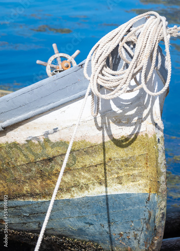 Close up bow of old wooden fishing boat with ropes and ships helm navigation wheel