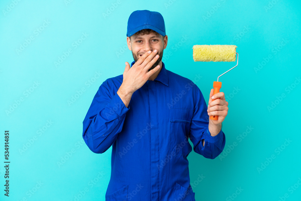 Painter caucasian man isolated on blue background happy and smiling covering mouth with hand Painter caucasian man isolated on blue background happy and smiling covering mouth with hand