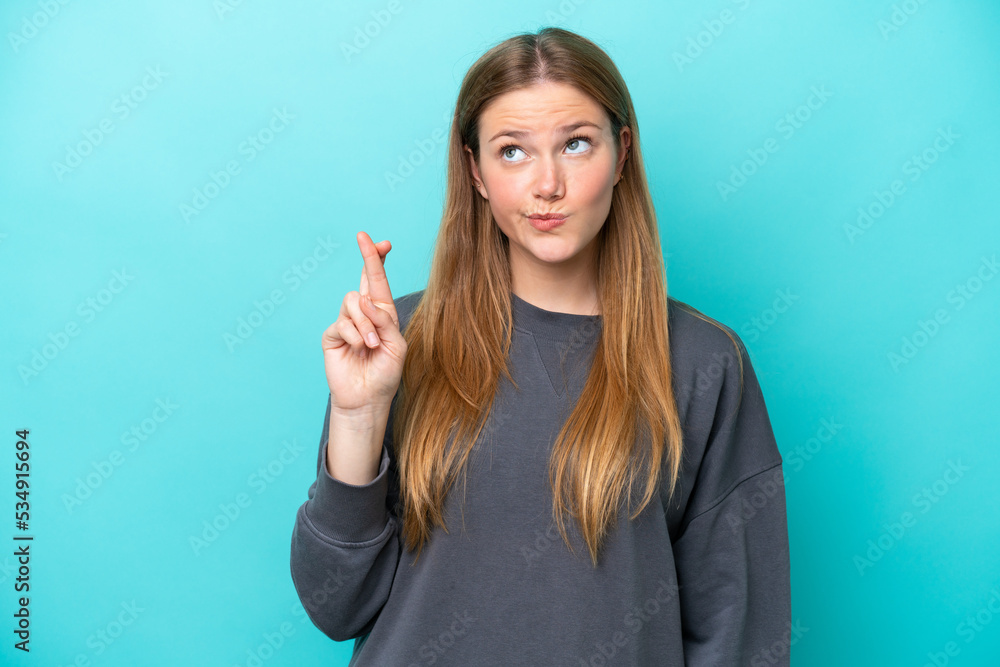 Young caucasian woman isolated on blue background with fingers crossing and wishing the best Young caucasian woman isolated on blue background with fingers crossing and wishing the best