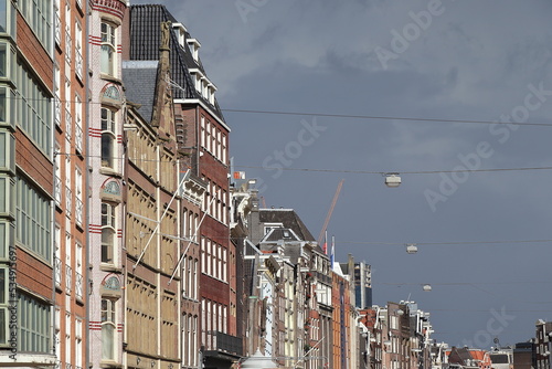 Amsterdam Nieuwezijds Voorburgwal Street House Facades View with Hanging Street Lights and Grey Sky, Netherlands