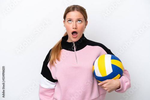 Young caucasian woman playing volleyball isolated on white background looking up and with surprised expression