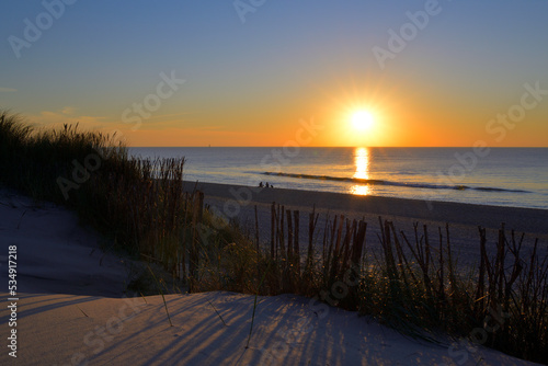 Sonnenuntergang   ber dem Meer und Menschen spazieren am Strand.