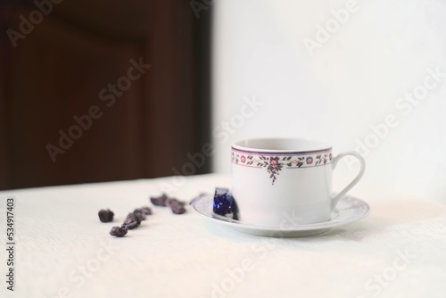 Tasse de thé violette et blanche avec des violettes cristallisées et un bonbon à la violette sur une petite table classique format portrait avec une zone vierge