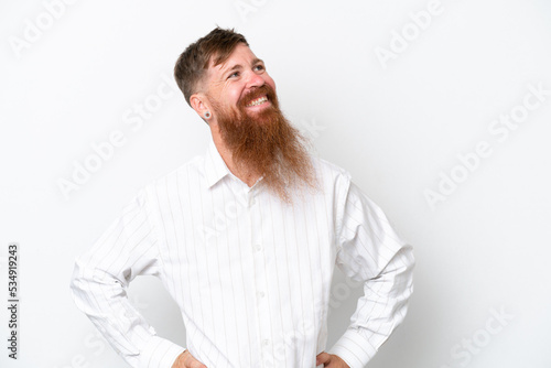 Redhead man with long beard isolated on white background posing with arms at hip and smiling © luismolinero