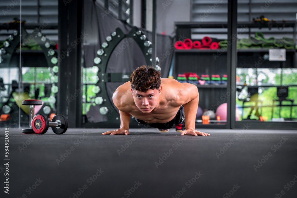 Fototapeta premium Portrait young fitness woman under push up exercise at gym. she exercise for strong ,make muscle body building and good healthy concept