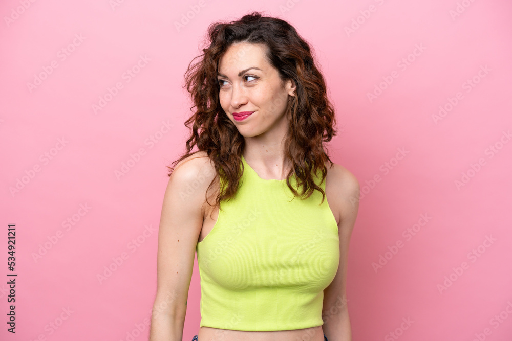 Young caucasian woman isolated on pink background having doubts while looking side Young caucasian woman isolated on pink background having doubts while looking side