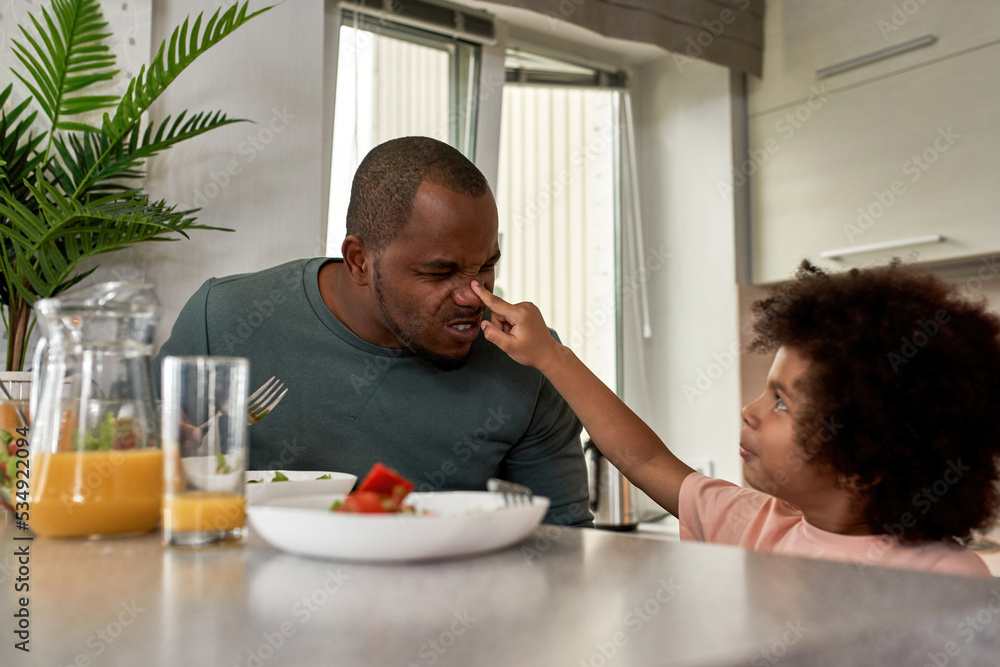 Boy touch nose of his father during having lunch Boy touch nose of his father during having lunch