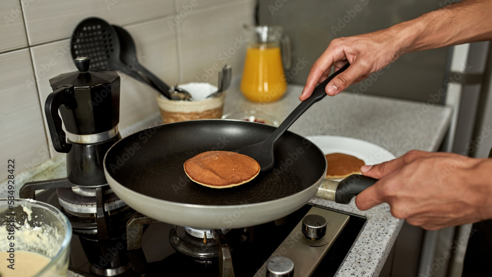 Cropped of man taking pancake after cooking on pan Cropped of man taking pancake after cooking on pan