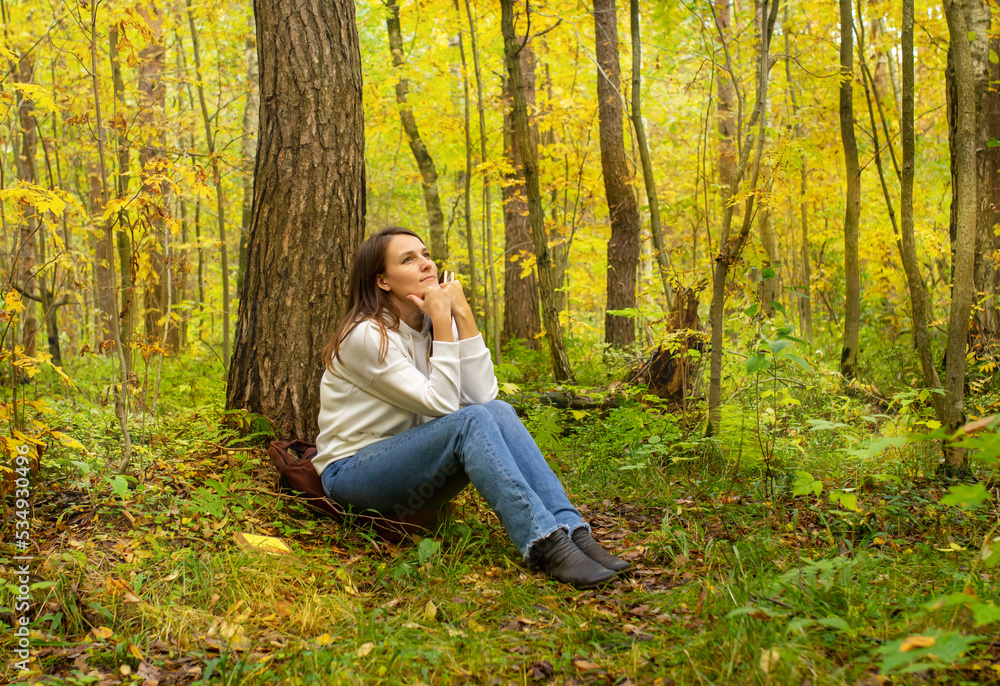 woman in the park sitting by a tree with a book woman in the park sitting by a tree with a book