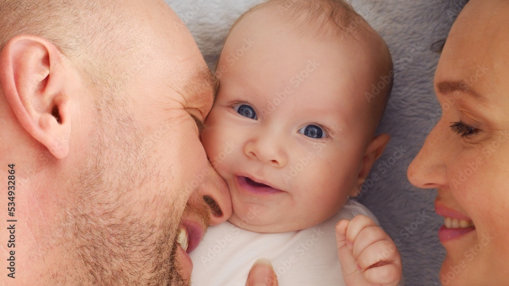 Happy parents with his newborn baby, top view. Happy family. Healthy newborn baby with mom and dad. Close up Faces of the mother, father and infant baby. Cute Infant boy and parents. Happy parents with his newborn baby, top view. Happy family. Healthy newborn baby with mom and dad. Close up Faces of the mother, father and infant baby. Cute Infant boy and parents.