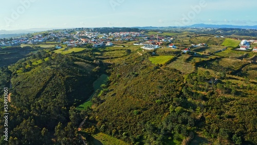 Top view of a European town with beautiful green landscape during sunset. Drone view of a beautiful small European city with a beautiful hilly landscape while sunset. Portugal.