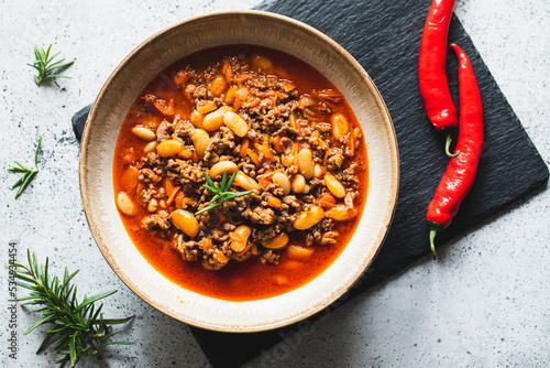 Chili Con Carne in bowl on light grey stone or concrete background. Mexican cuisine. chili con carne - minced meat and vegetables stew in tomato sauce. Top view