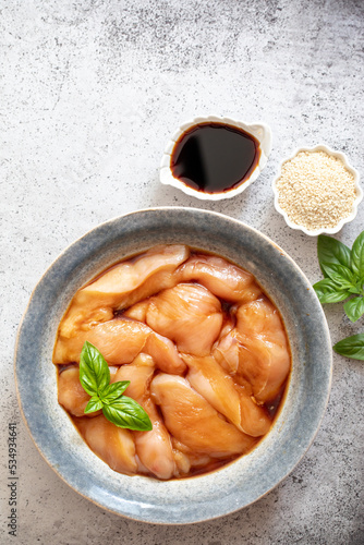 Raw diet marinated chicken meat with teriyaki sauce in a grey bowl. Marinating meat for cooking barbecue