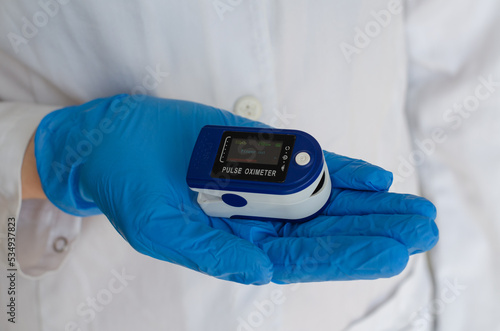 Device for measuring saturation. Medical device. A doctor wearing rubber gloves measures a patient's vital signs.