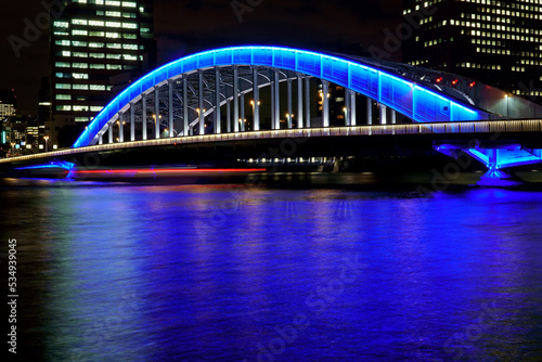 ブルーにライトアップされた永代橋と屋形船の軌跡