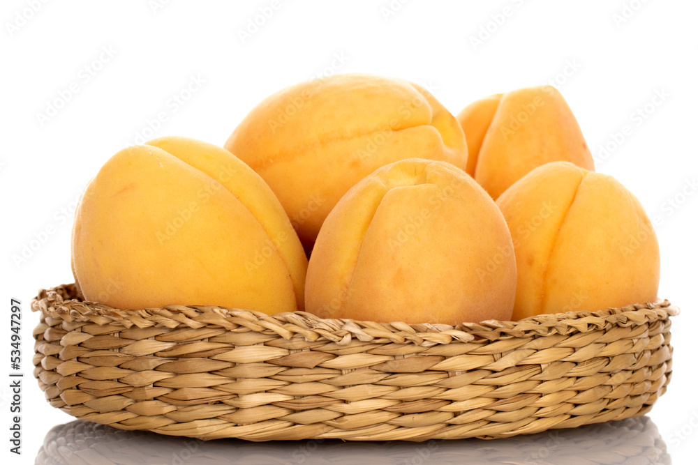 Several ripe pineapple apricots in a straw plate, close-up, isolated on white. Several ripe pineapple apricots in a straw plate, close-up, isolated on white.