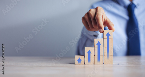 Canvastavla businessman hand  arranging wood block stacking as step stair with arrow up