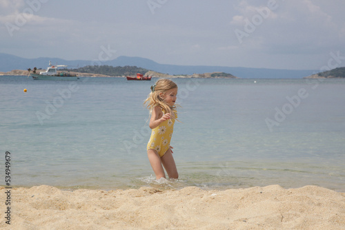 Cheerful little 4 years old girl playing and jumping on the sand beach