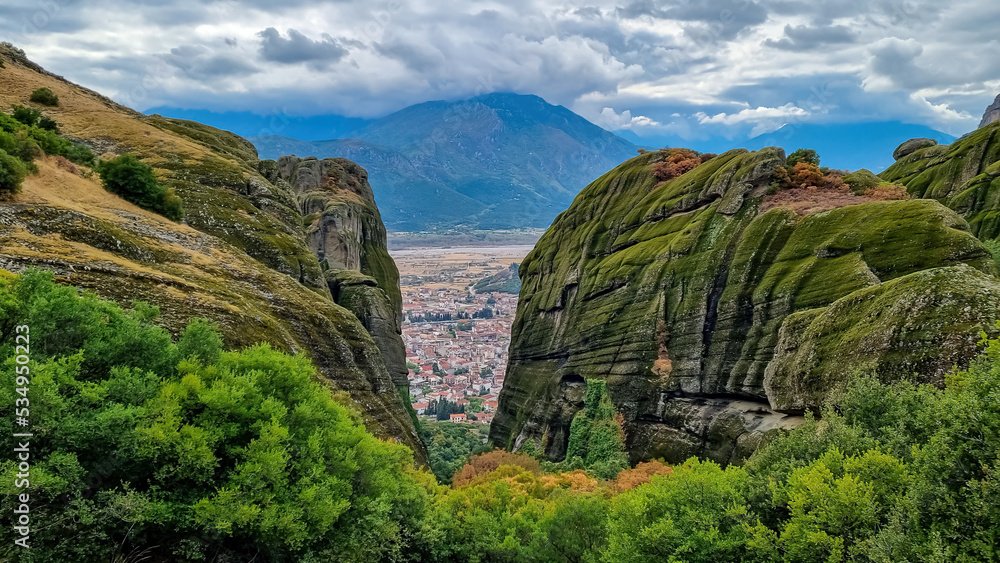Scenic aerial view of tourist village of Kalambaka, Thessaly, Greece, Europe, Pindus mountains. Dramatic rock complex of Meteora seen from Holy Trinity Monastery build on moss overgrown rock formation