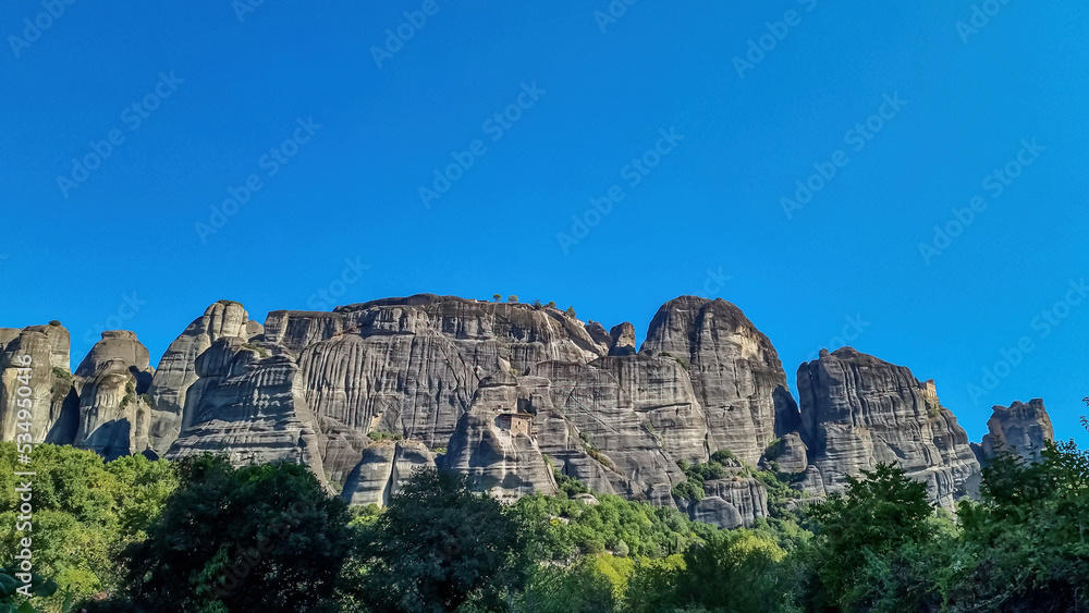 Scenic view of Holy Monastery of St Nicholas Anapafsas seen from forest near Kalambaka, Meteora, Thessaly, Greece, Europe. Dramatic landscape. Landmark build on rock formation. Massive rock cliff wall