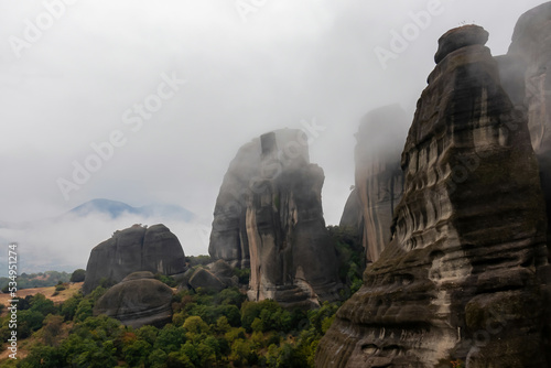 Panoramic morning view of unique rock formation seen from Holy Monastery of Rousanou in Kalambaka, Meteora, Thessaly, Greece, Europe. Rocks are surrounded by mystical fog. Moody dramatic atmosphere