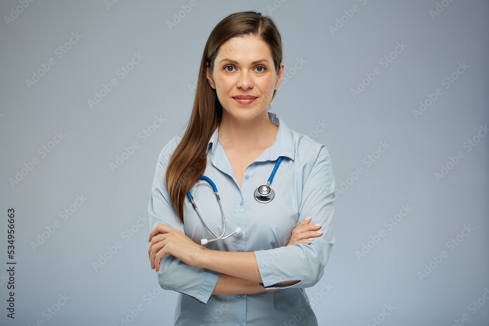 Smiling doctor woman holding stethoscope standing with arms crossed. Isolated portrait of female medical worker on blue background. Smiling doctor woman holding stethoscope standing with arms crossed. Isolated portrait of female medical worker on blue background.