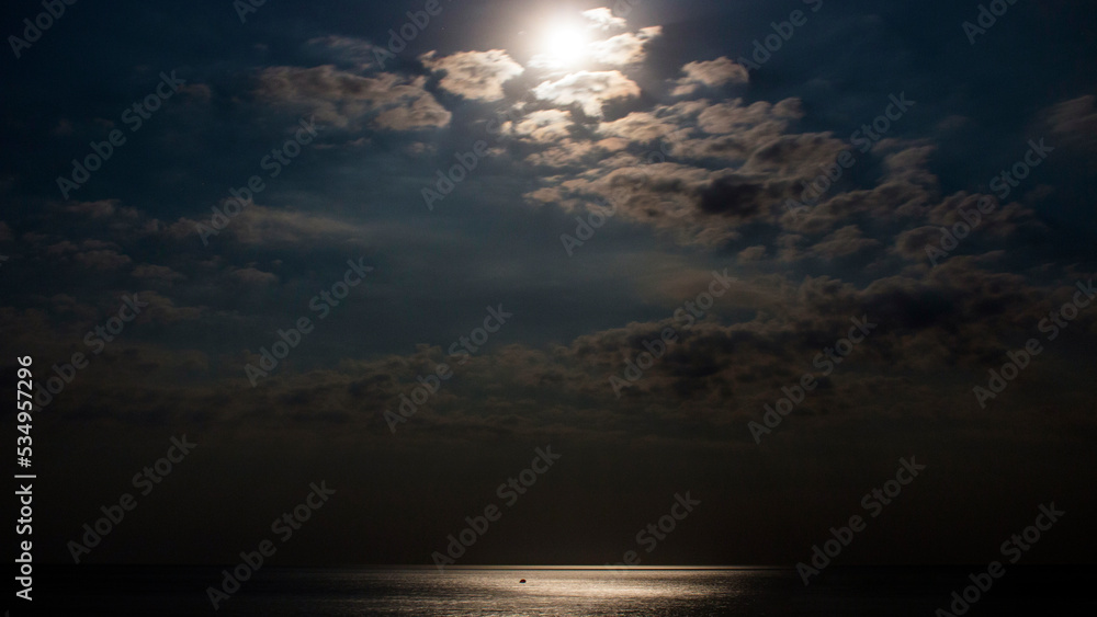 Night sky with moon among the clouds on the sea