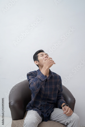 a man wearing a plaid shirt sitting very sleepy