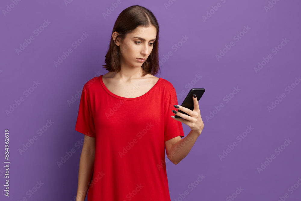 I'm tired of this gadgets. Pensive young pretty brunette girl in red t-shirt using smartphone texting. Thoughtful serious looks on screen. I cannot stop browsing internet. Posing over purple wall. I'm tired of this gadgets. Pensive young pretty brunette girl in red t-shirt using smartphone texting. Thoughtful serious looks on screen. I cannot stop browsing internet. Posing over purple wall.