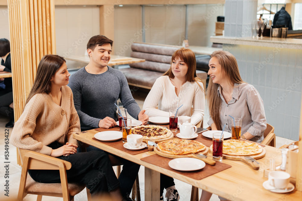 A group of friends is having pizza in a cozy restaurant. Meeting friends over dinner, socializing with a friendly company. A group of friends is having pizza in a cozy restaurant. Meeting friends over dinner, socializing with a friendly company.