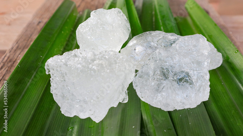 Crystal clear alum cubes or Potassium alum on green leaf. Chemical compound substance. Concept for beauty , spa and underarm treatment industrial. 