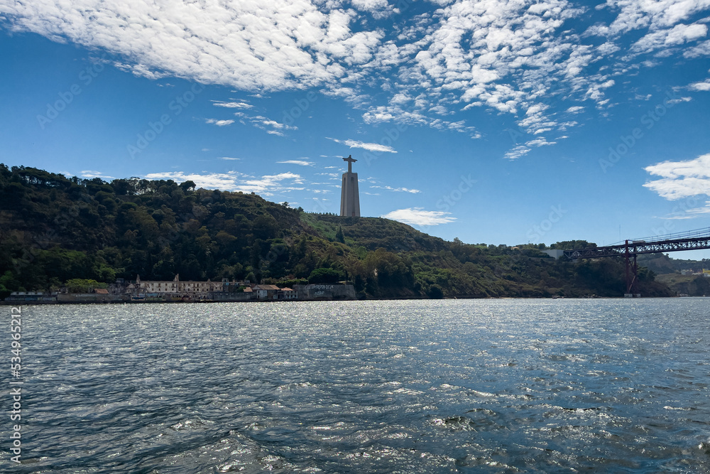 View from a ferryboat passing by Christ the King statue in Lisbon