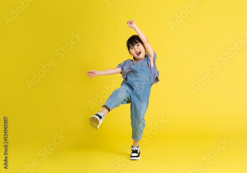 full body image of beautiful asian baby girl on yellow background