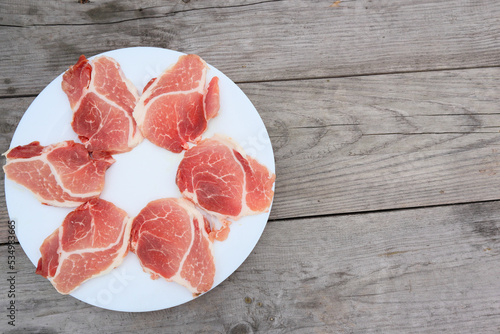 Raw Pork Slice in White Round Plate on old Wooden Table. Slide raw meat on the table. Top view