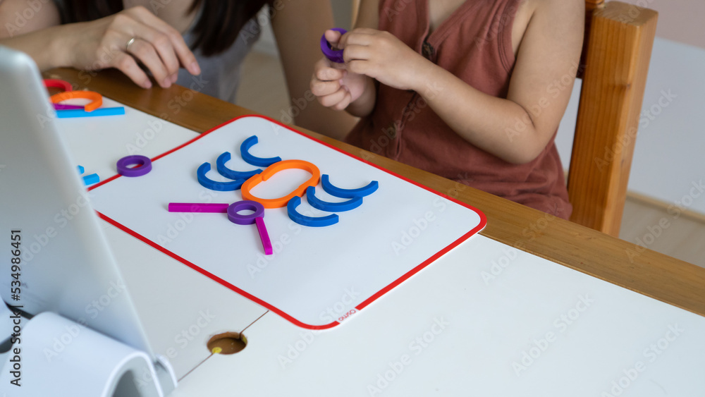 at the classroom, a girl is learning to arrange and form complex figures from simple shaped rubber blocks at the classroom, a girl is learning to arrange and form complex figures from simple shaped rubber blocks