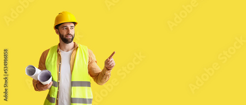 Builder with drawings pointing at something on yellow background with space for text