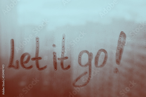 Fotografie Hand drawn message Let it go on foggy glass on city window