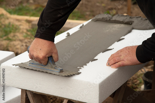 thermal insulation. Close-up of worker hand, applying glue on white rigid polyurethane foam sheet