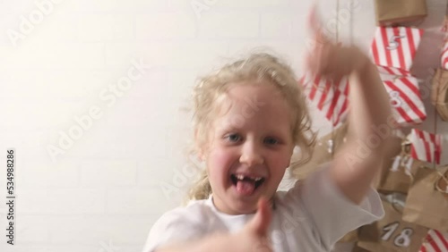 cute curly girl with blond hair and advent calendar, homemade gift advent calendar with surprises, advent tradition, christmas eve, winter holidays