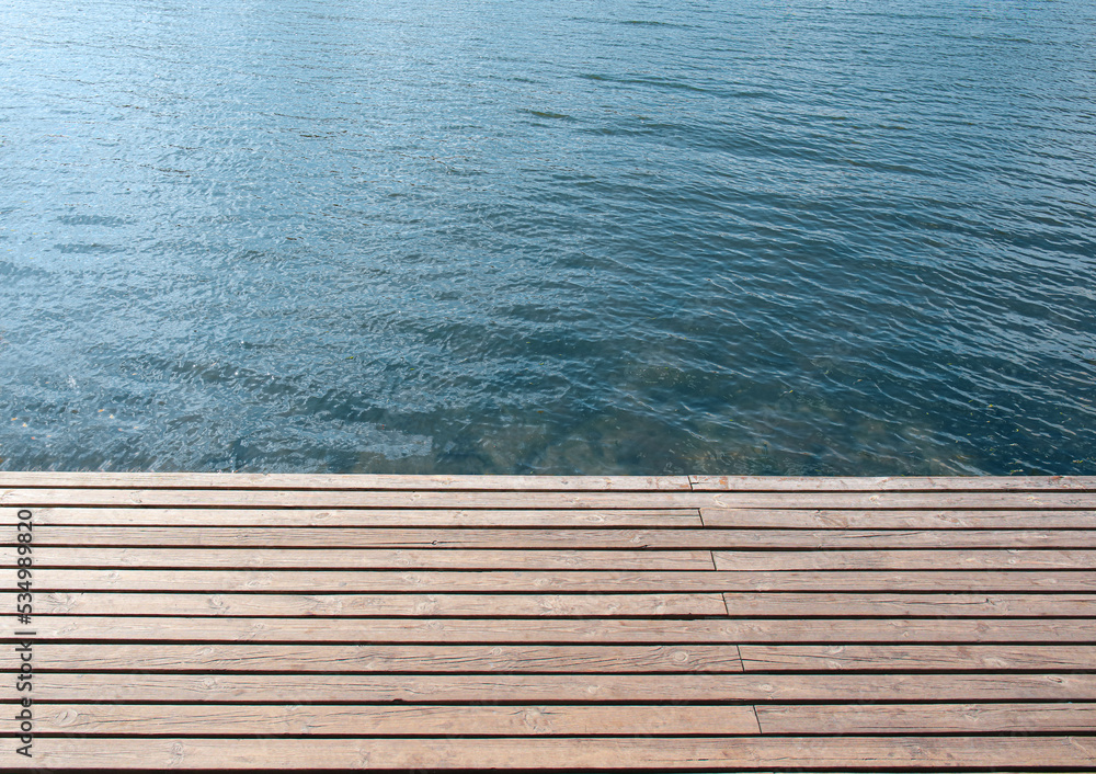 Closeup view of wooden pier near calm blue water Closeup view of wooden pier near calm blue water