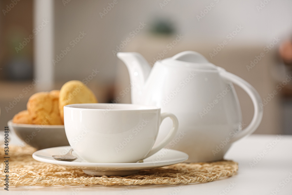 Cup of hot tea and pot on table in cafe Cup of hot tea and pot on table in cafe