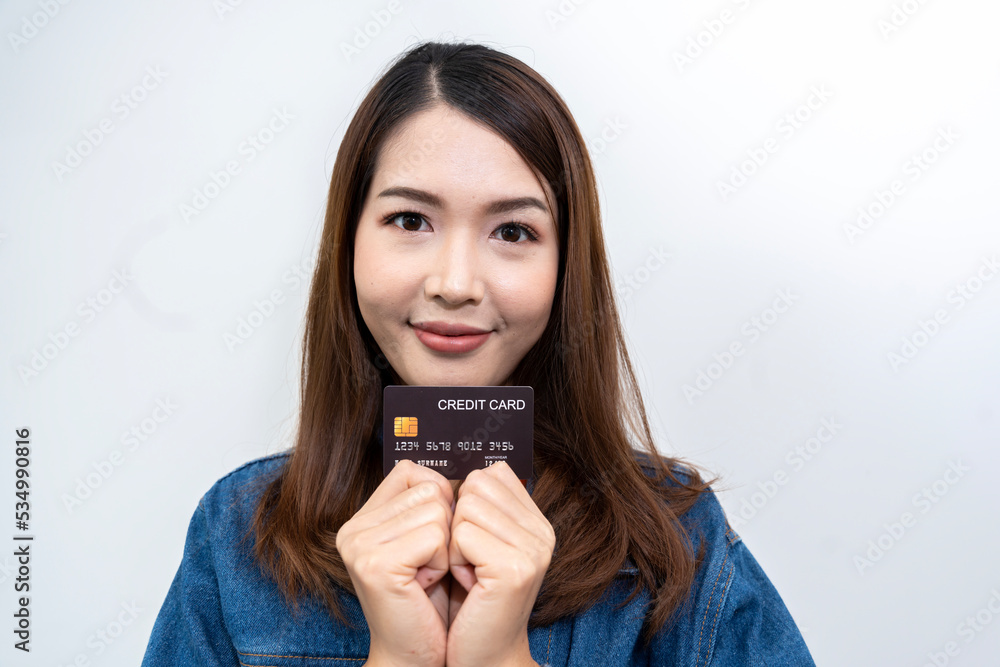 Portrait of an Asian woman in Thailand wearing a blue jeans and an orange T-shirt. Enjoy using your credit card on your mobile phone. isolated white background