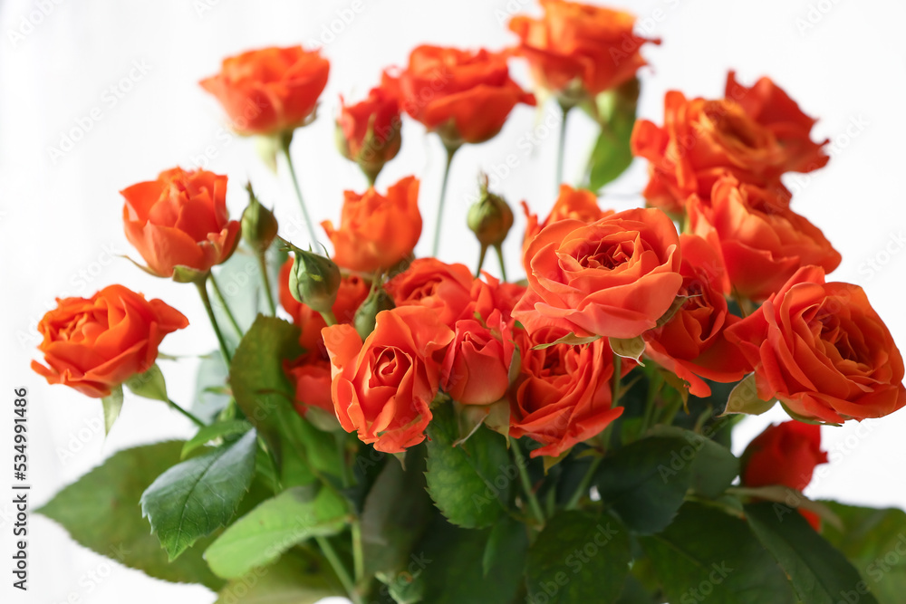 Fototapeta premium romance and celebration, bouquet of vibrant orange roses for wedding anniversary or valentines day gift with green leaves isolated on white background