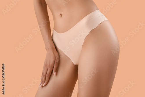 Slim young woman in underwear on beige background, closeup