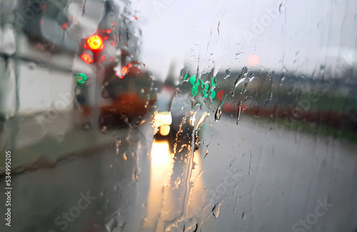 Blurred view of city traffic through wet car window with rain drops