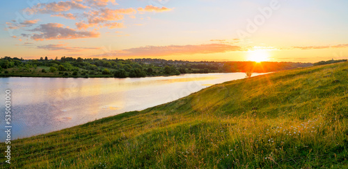 Summer sunny landscape with sun rising over the blue calm river and green hills. photo